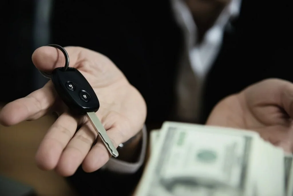 Car key and cash held out during a vehicle sale