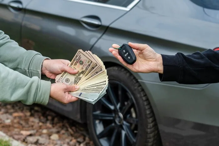 Car keys and cash being exchanged beside a vehicle